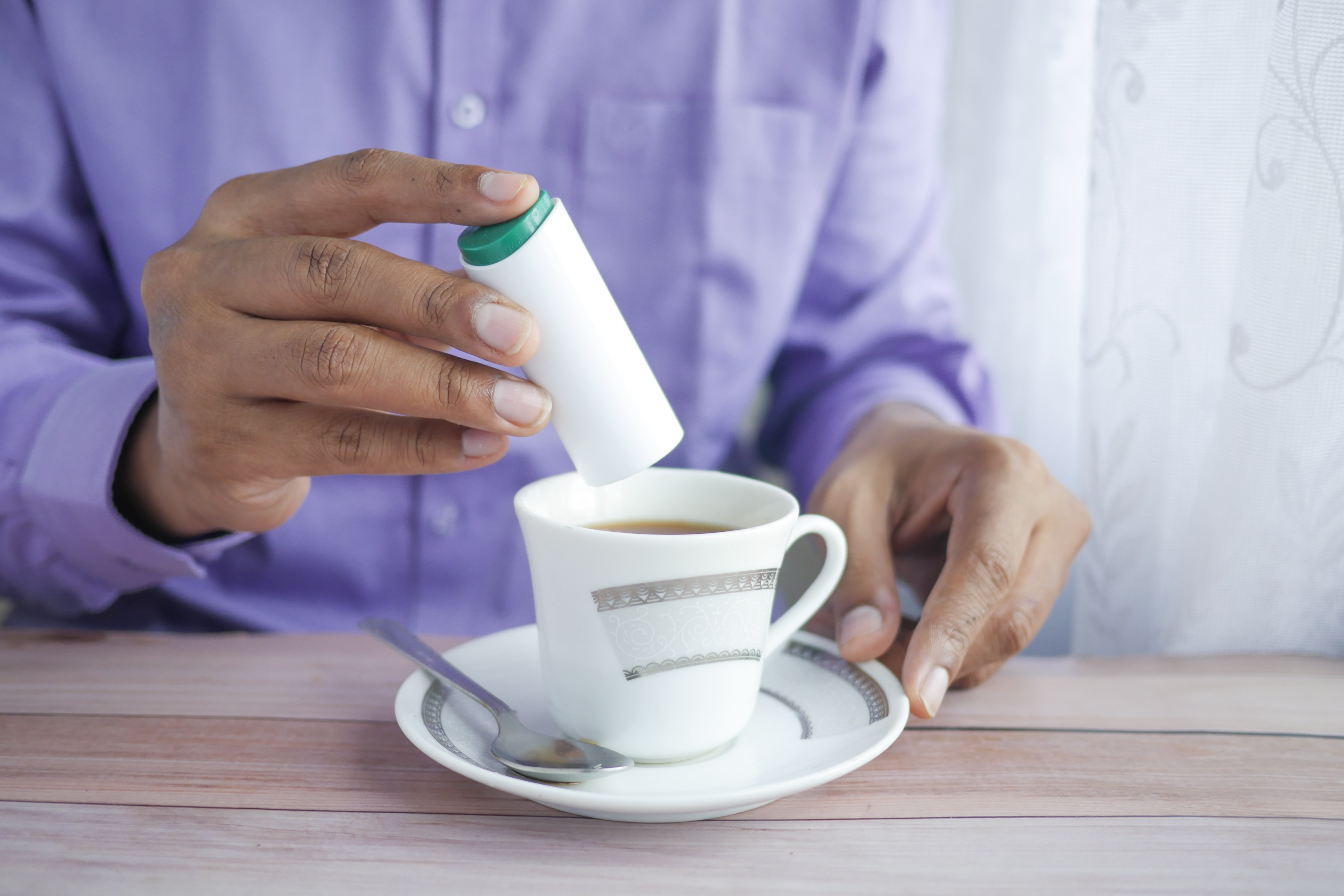 Man adds sweetener to his coffee