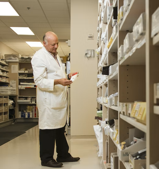 A pharmacist picks up a drug from pharmacy inventory