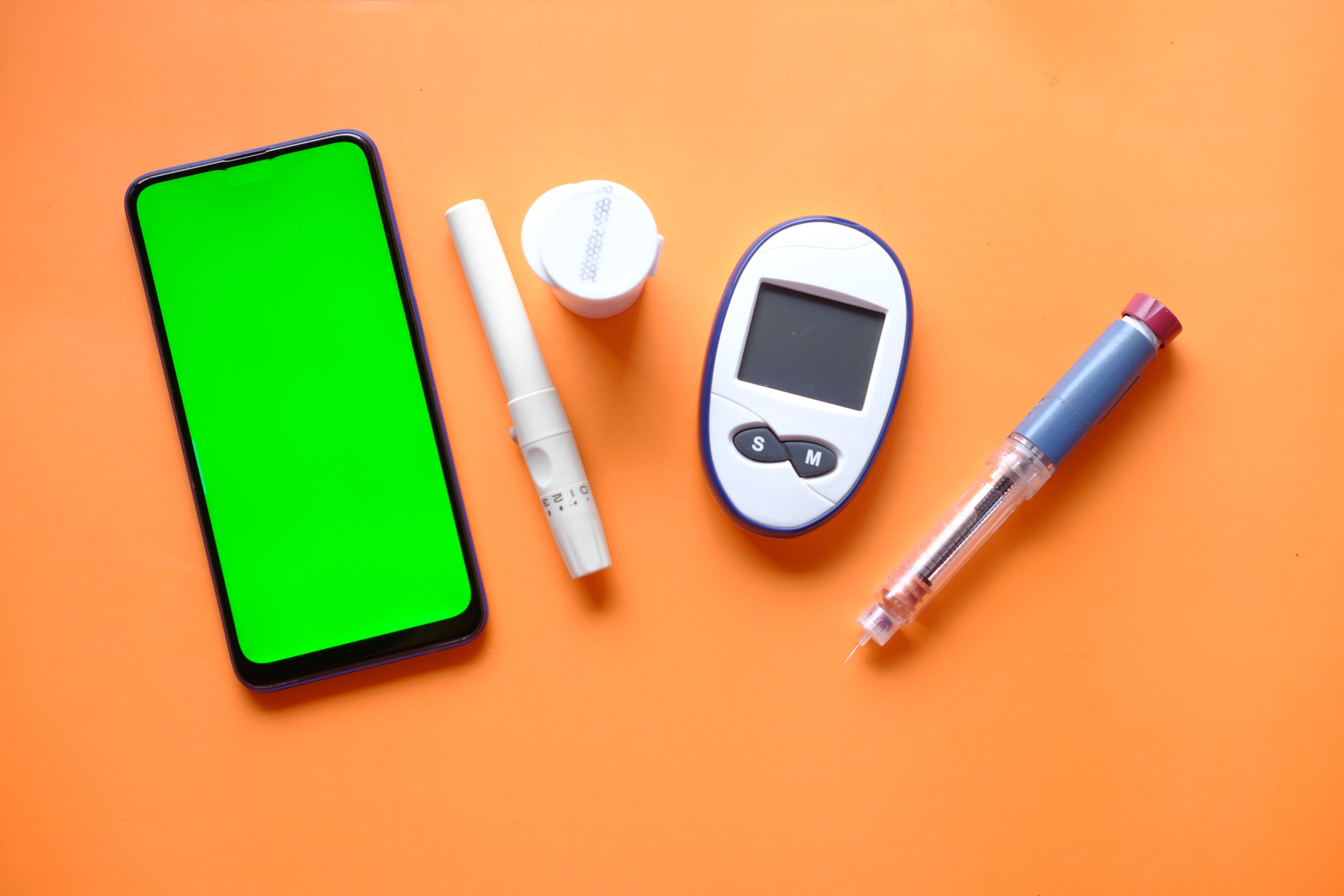 insulin pen, diabetic measurement tools an smart phone with empty space on table